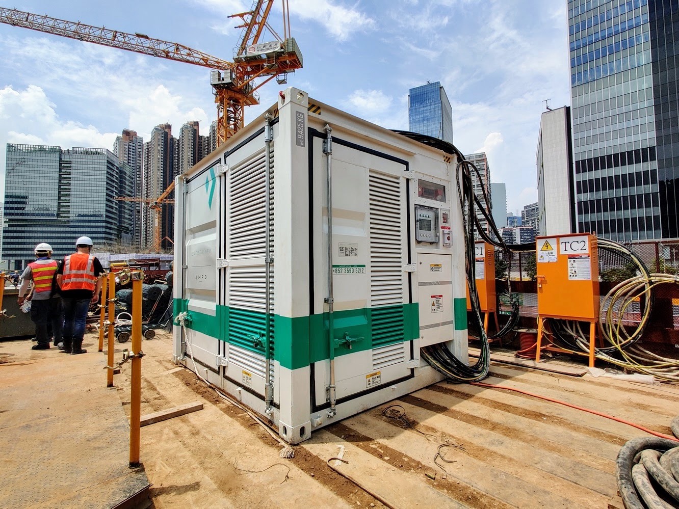 Containerized battery energy storage unit powering a tower crane on a high-rise construction site